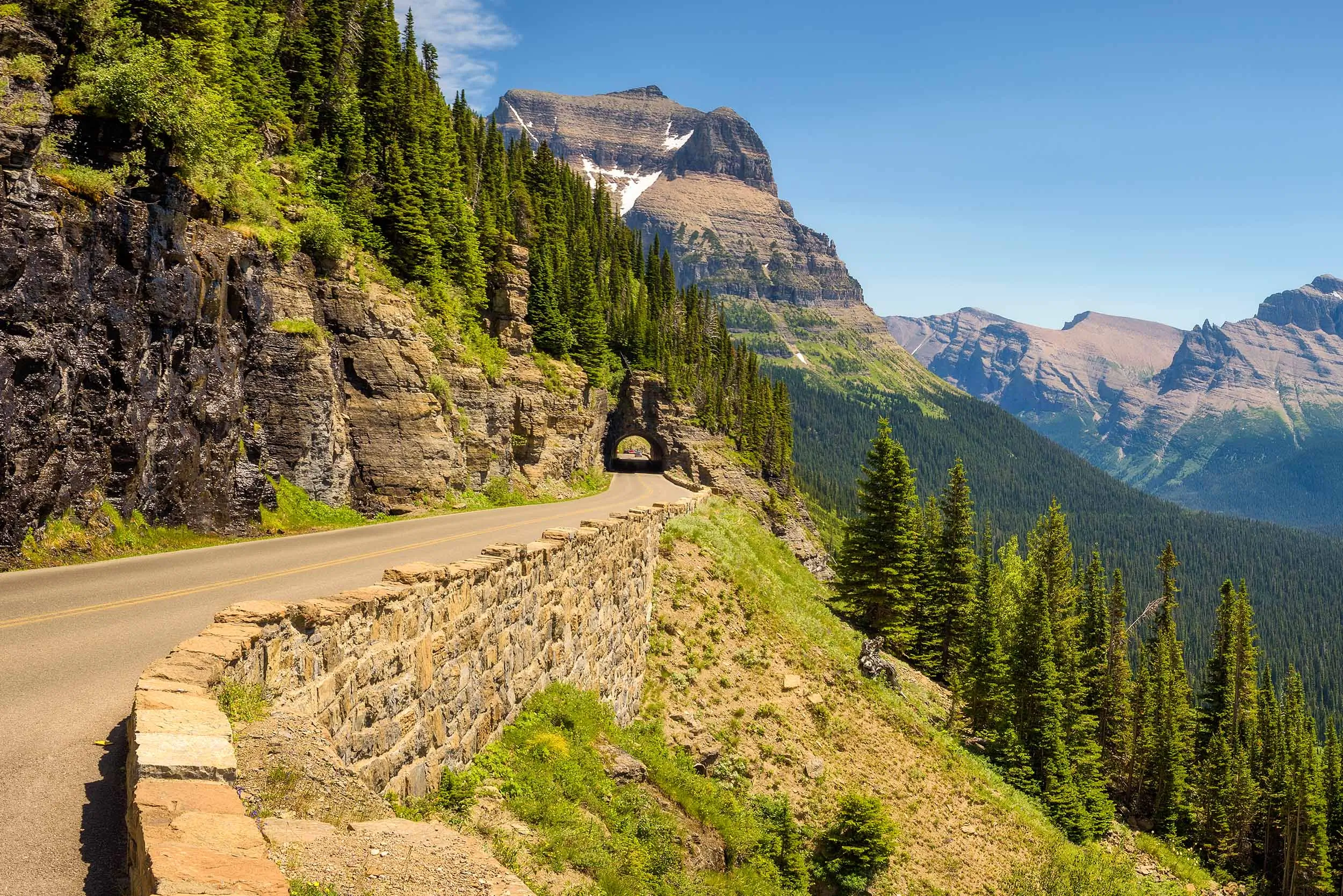 a road winds through a tunnel with mountains in the background 