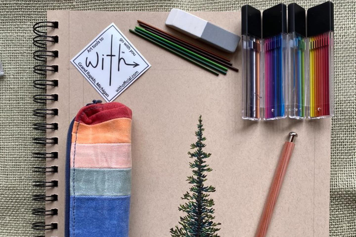 a colored pencil set resting on a drawing of a tree