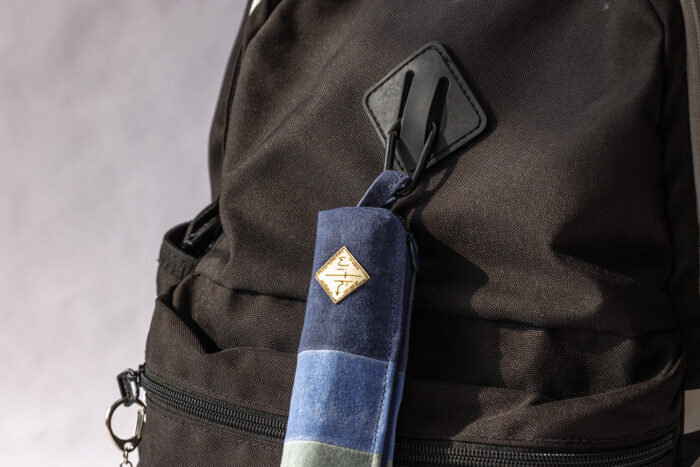 The With waxed canvas bag clipped to a backpack