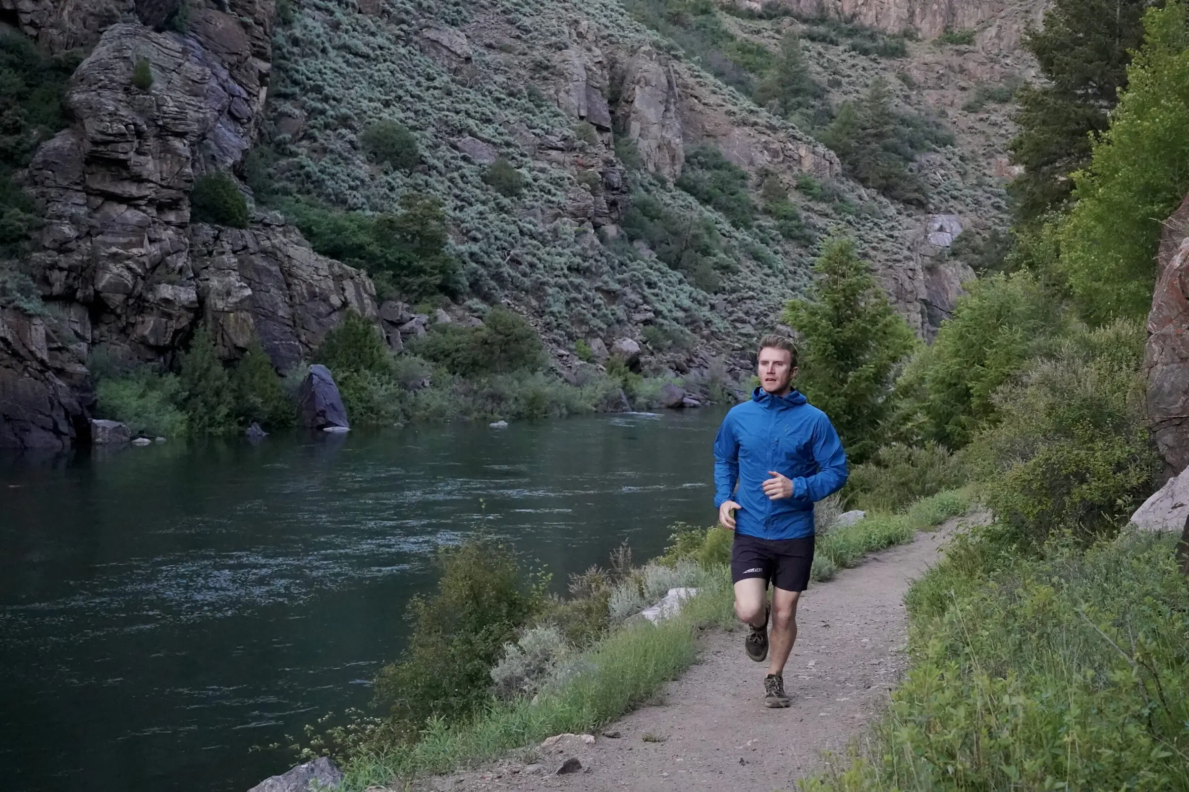 Man runs down trail with trail running shoes