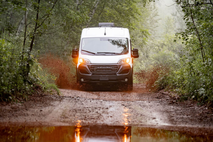 A Winnebago Solis Pocket 36B splashes through a mud puddle