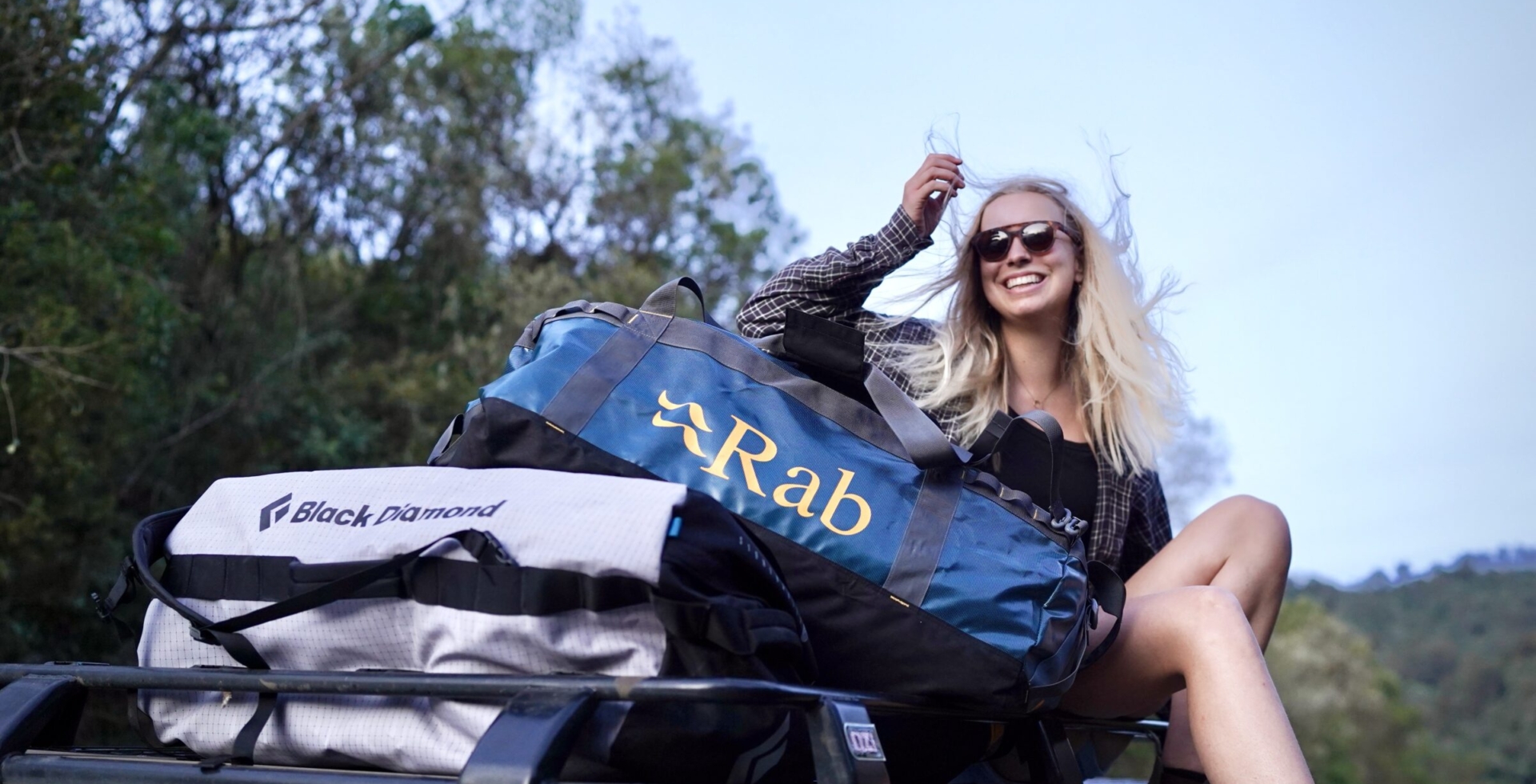 Woman with duffel bags on the roof rack of a truck