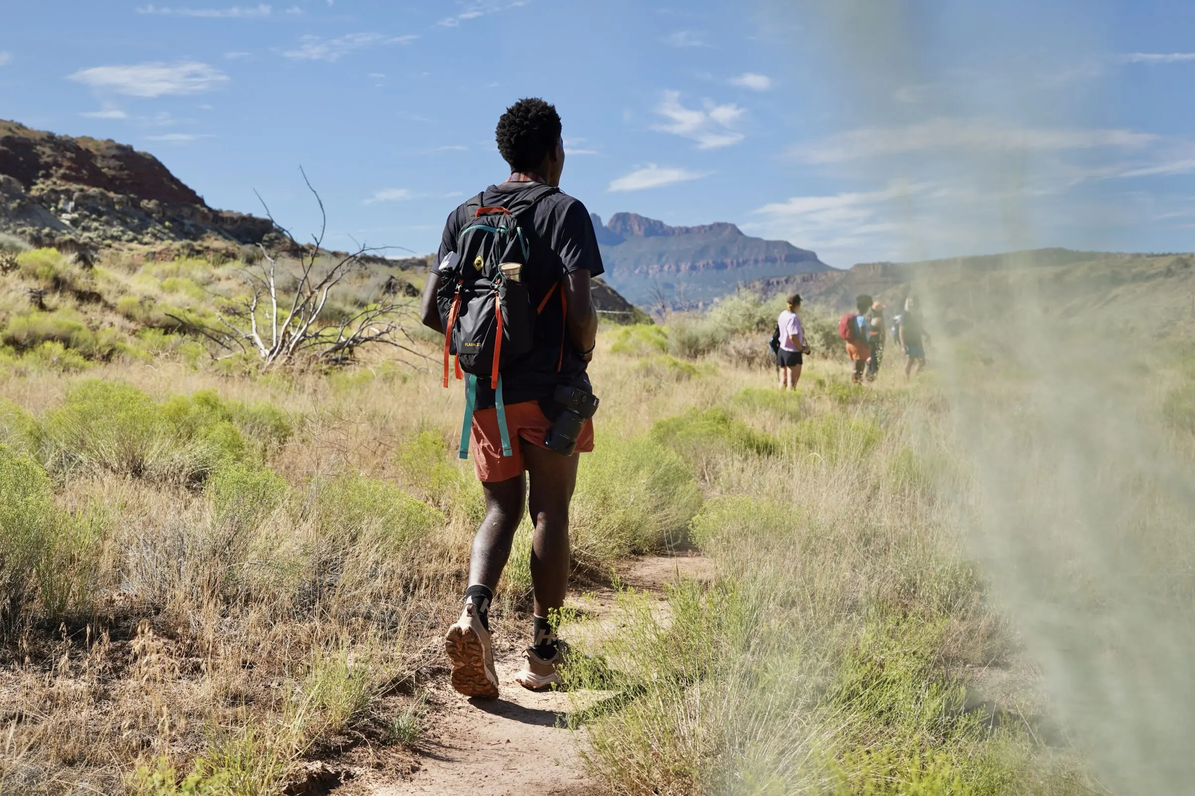 A man walks down a trail while wearing hiking boots