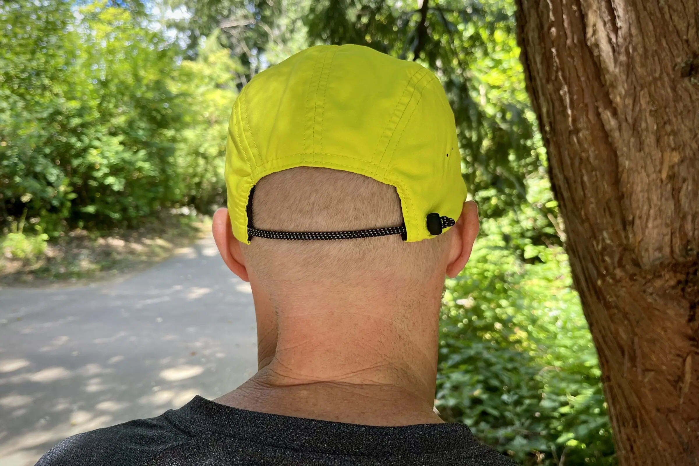 A man wears a running hat on a trail