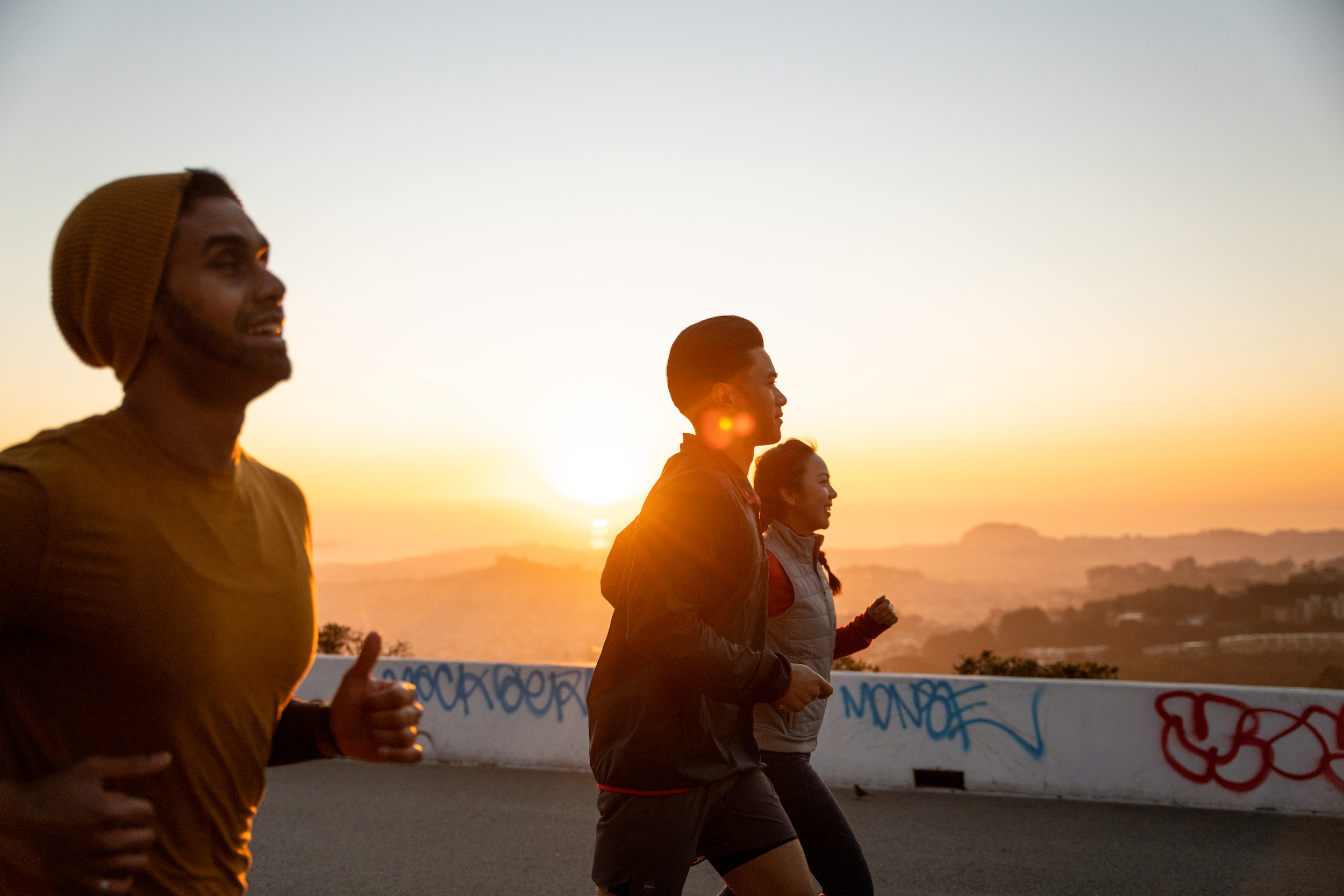 three people running outside at sunset for rei sale labor day