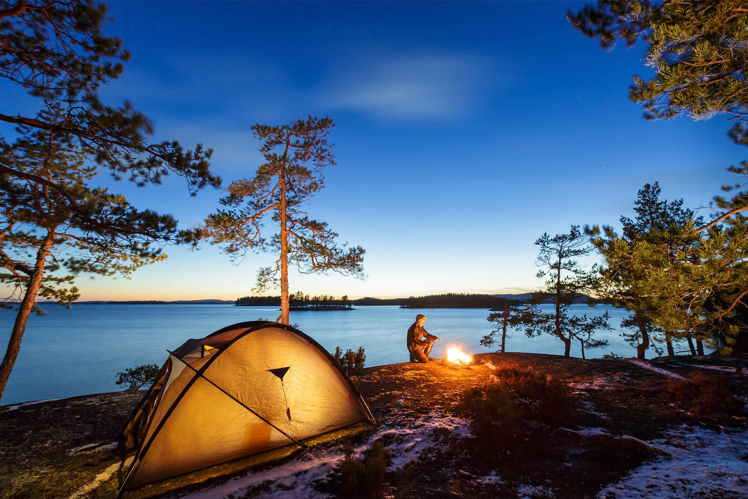 a fire and tent next to a beautiful lake