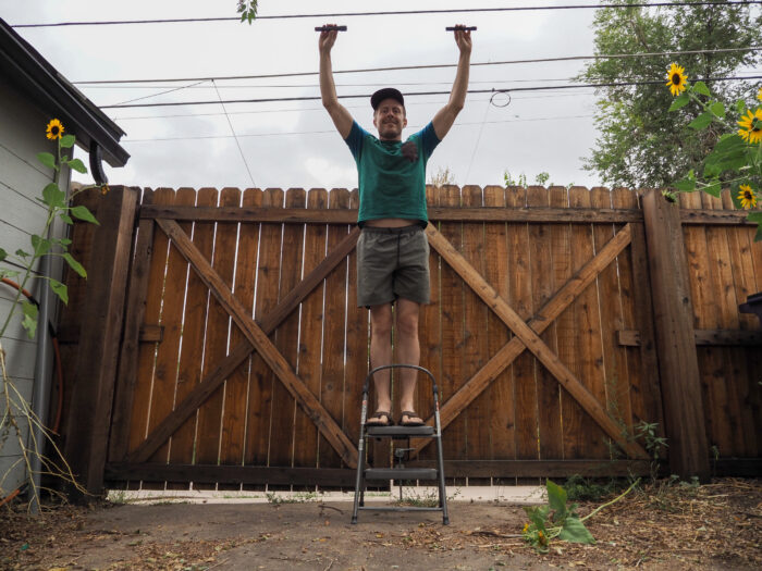 Man holds two flashlights while on step stool