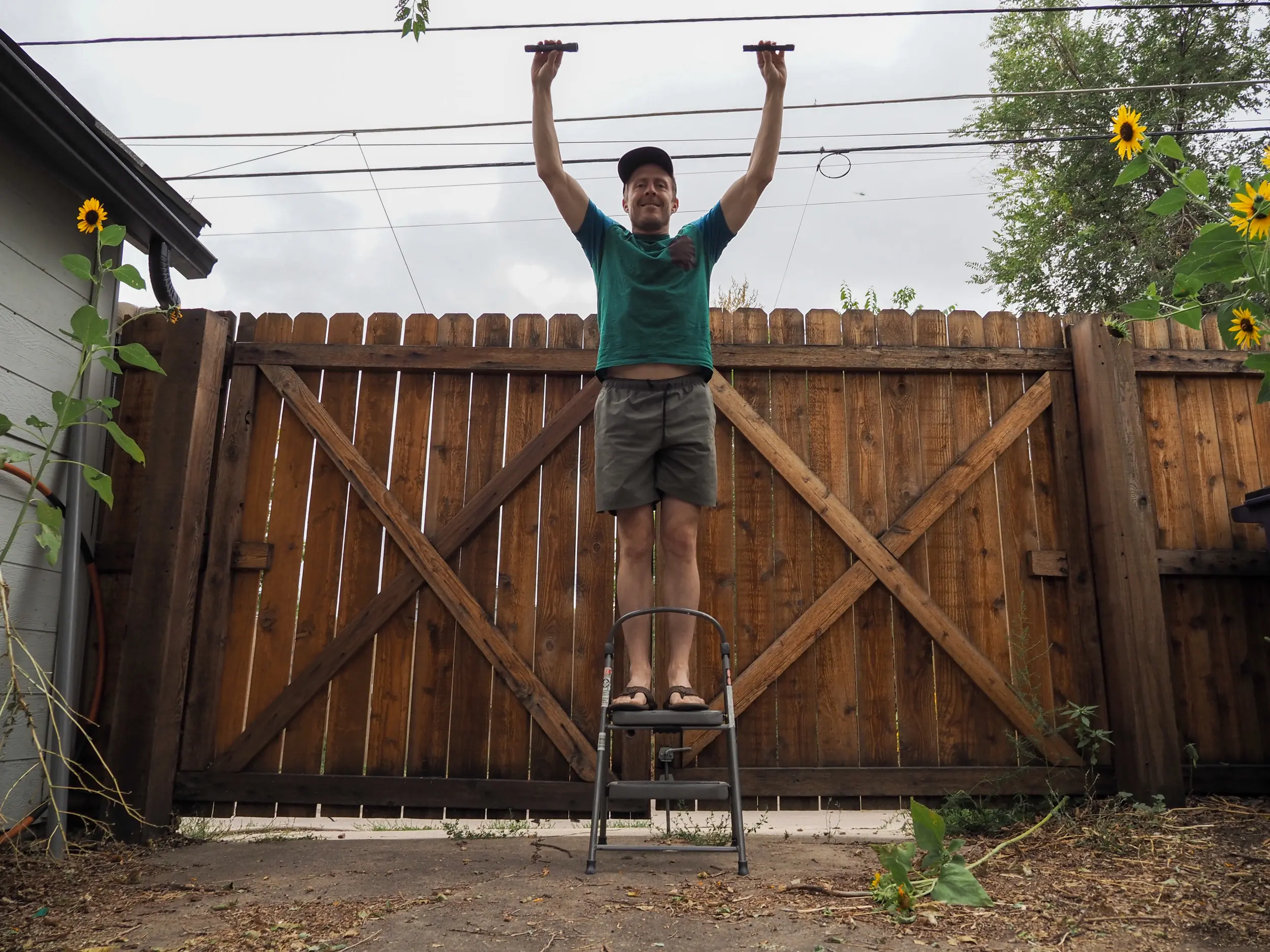 Man holds two flashlights while on step stool