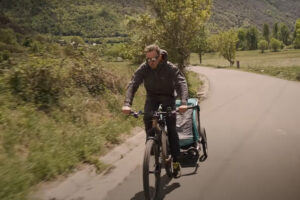 a man rides a bicycle while towing a bike trailer