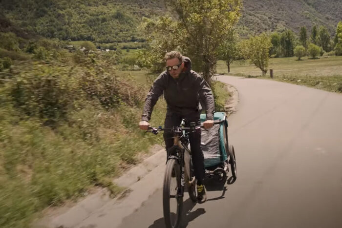 a man rides a bicycle while towing a bike trailer