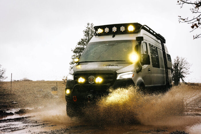 a modified sprinter van splashes through a puddle