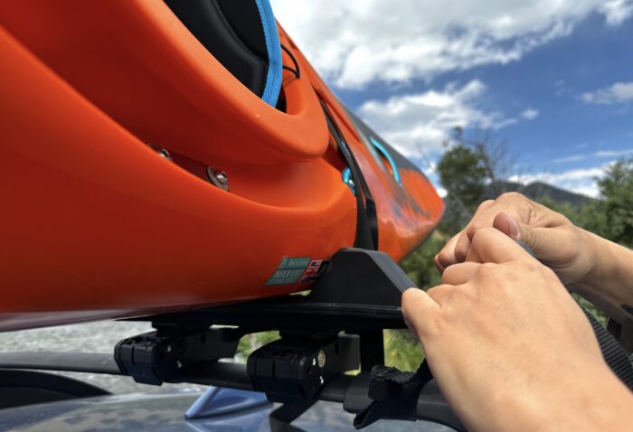 tying on straps to secure the kayak to the Kuat roof kayak rack