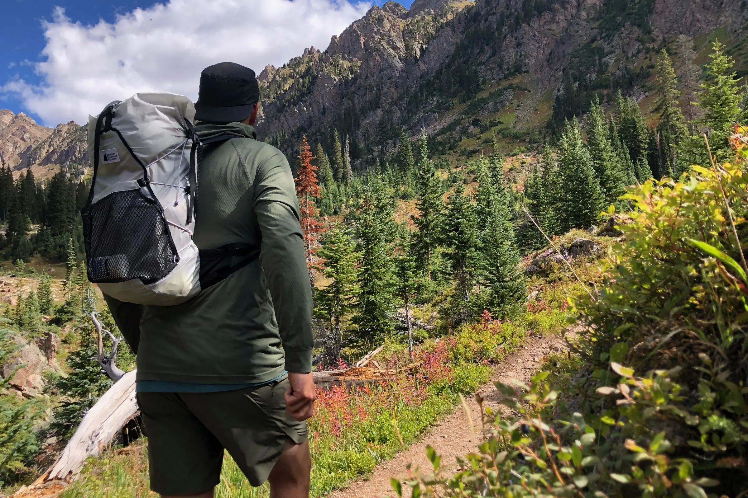 author wearing the mec serratus 25 backpack on a hiking trail in front of a mountain