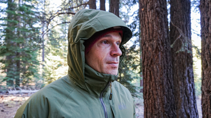 A man demonstrating the hood on the REI Stormhenge Down Hybrid Parka