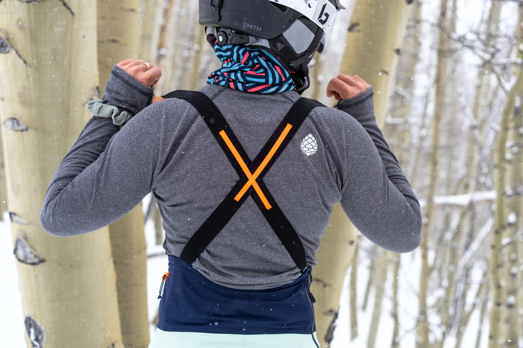 woman faces away from camera wearing a criss-crossed ski bib