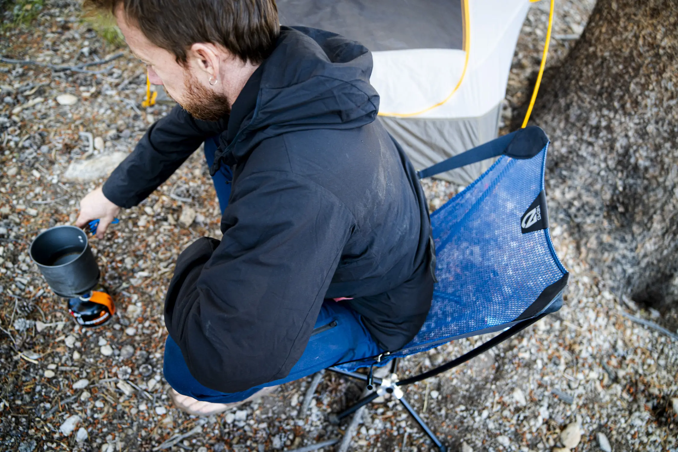 A man sits down into a NEMO backpacking chair