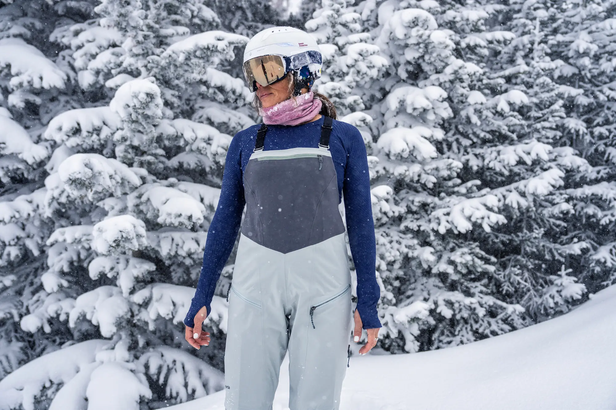 woman facing camera stand in chest-high ski bibs