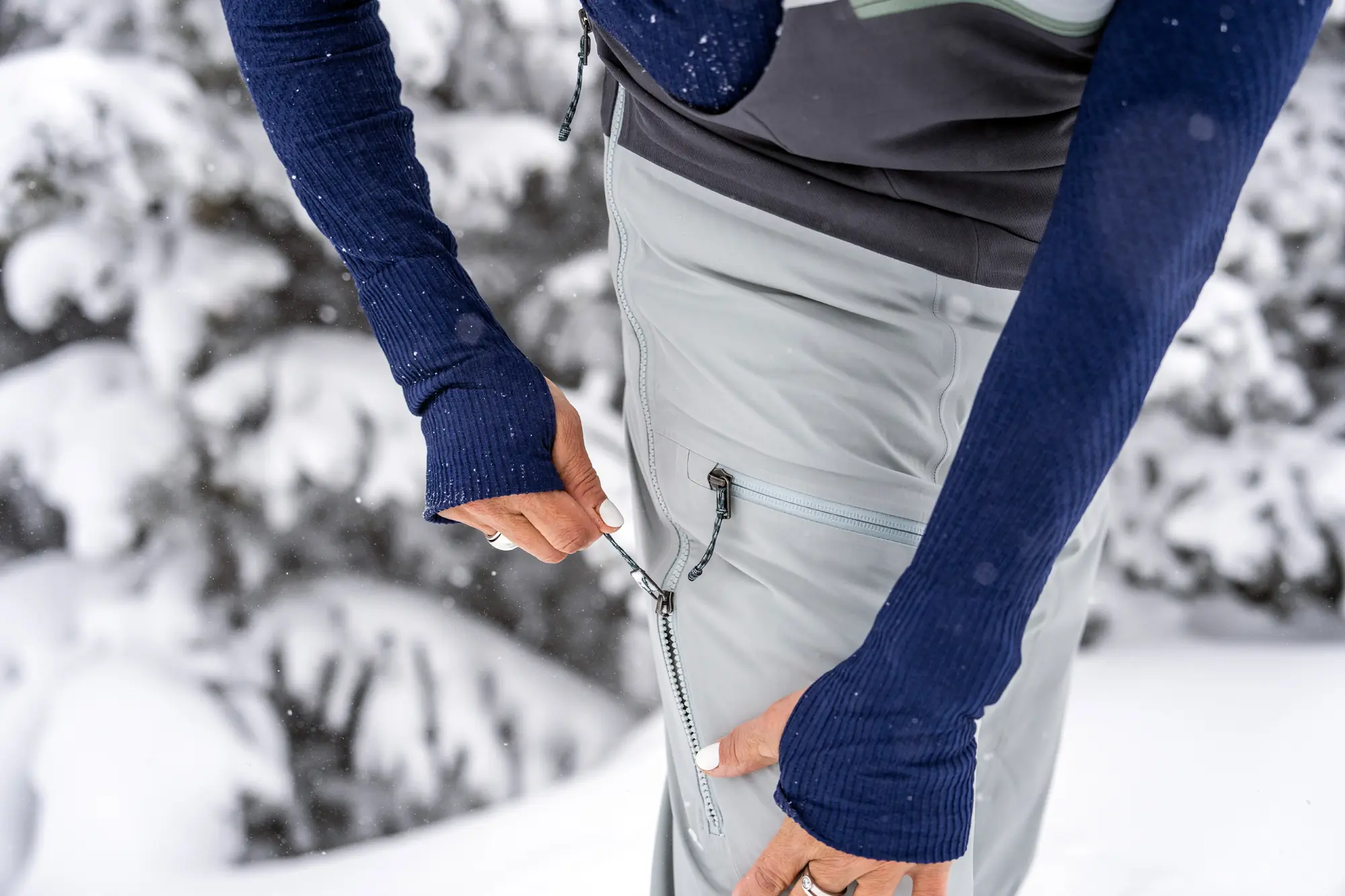 woman pulls zip tab on vent on ski bibs 