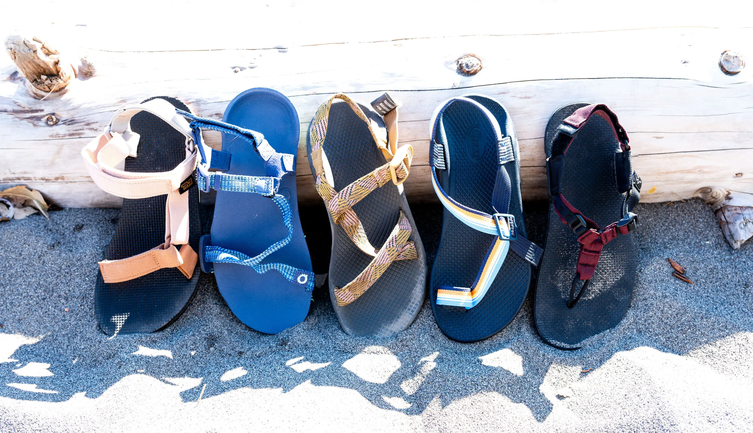 a lineup of different hiking sandals on a beach