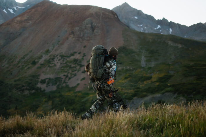 Author carrying hunting gear over mountainous landscape