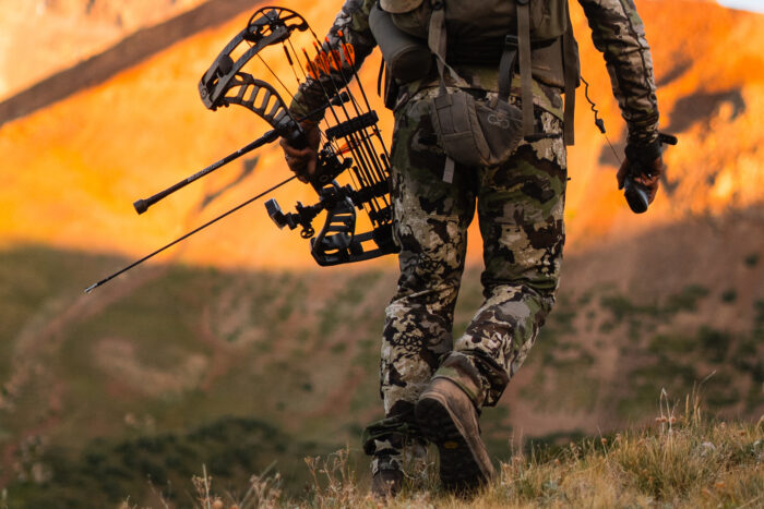 hunter walking holding a bow wearing the pnuma's Pursuit Pant