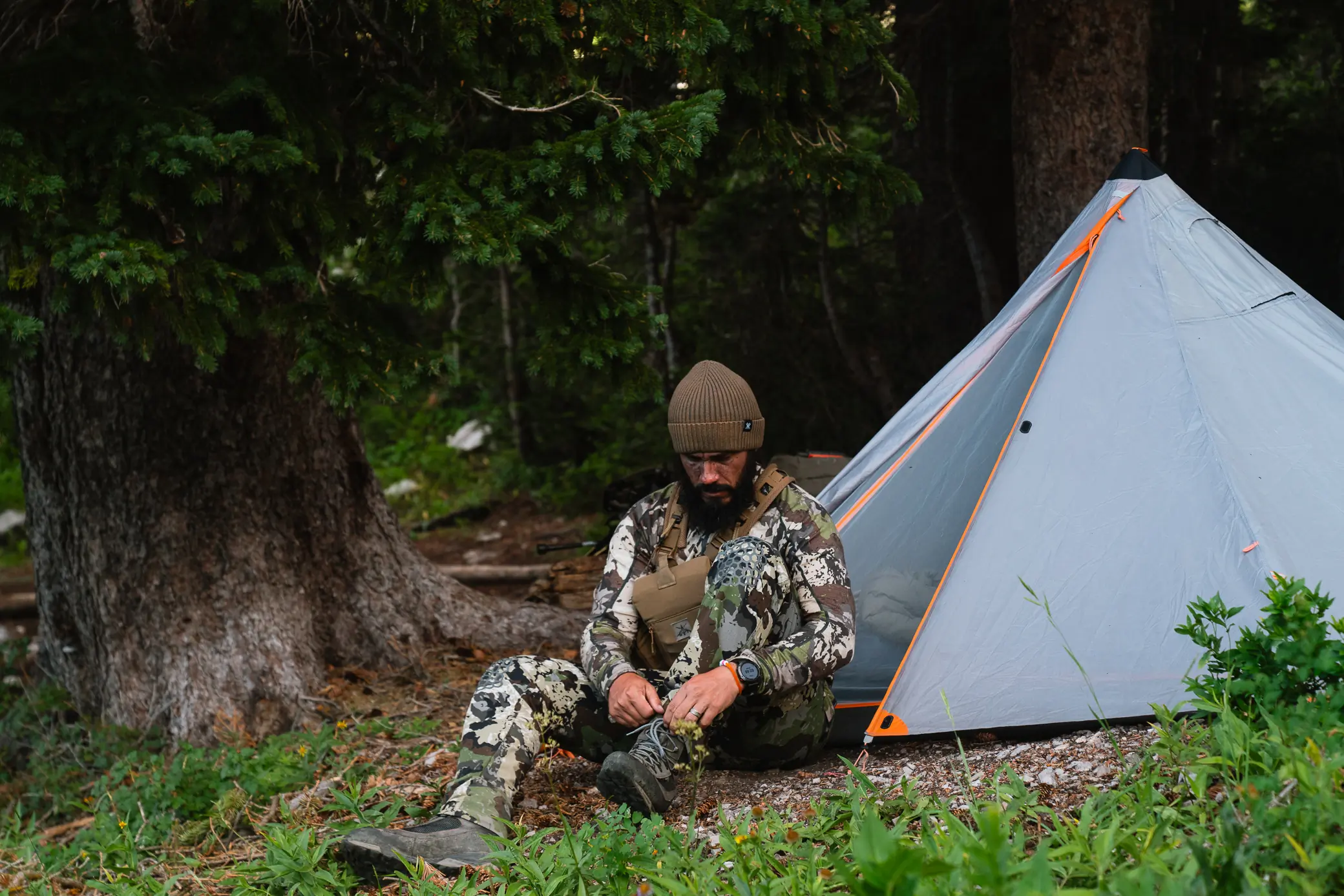 Author tying his shoes near his camp wearing Pnuma Outdoors Layering System