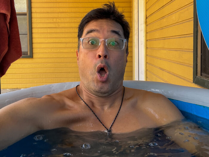 Man getting in cold plunge tub with shocked face