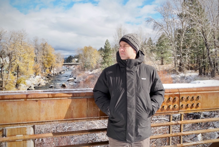 a man standing on a footbridge wearing a black Patagonia Stormshadow Jacket.