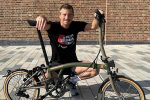 Adventurer Bear Grylls poses with a foldable bicycle.