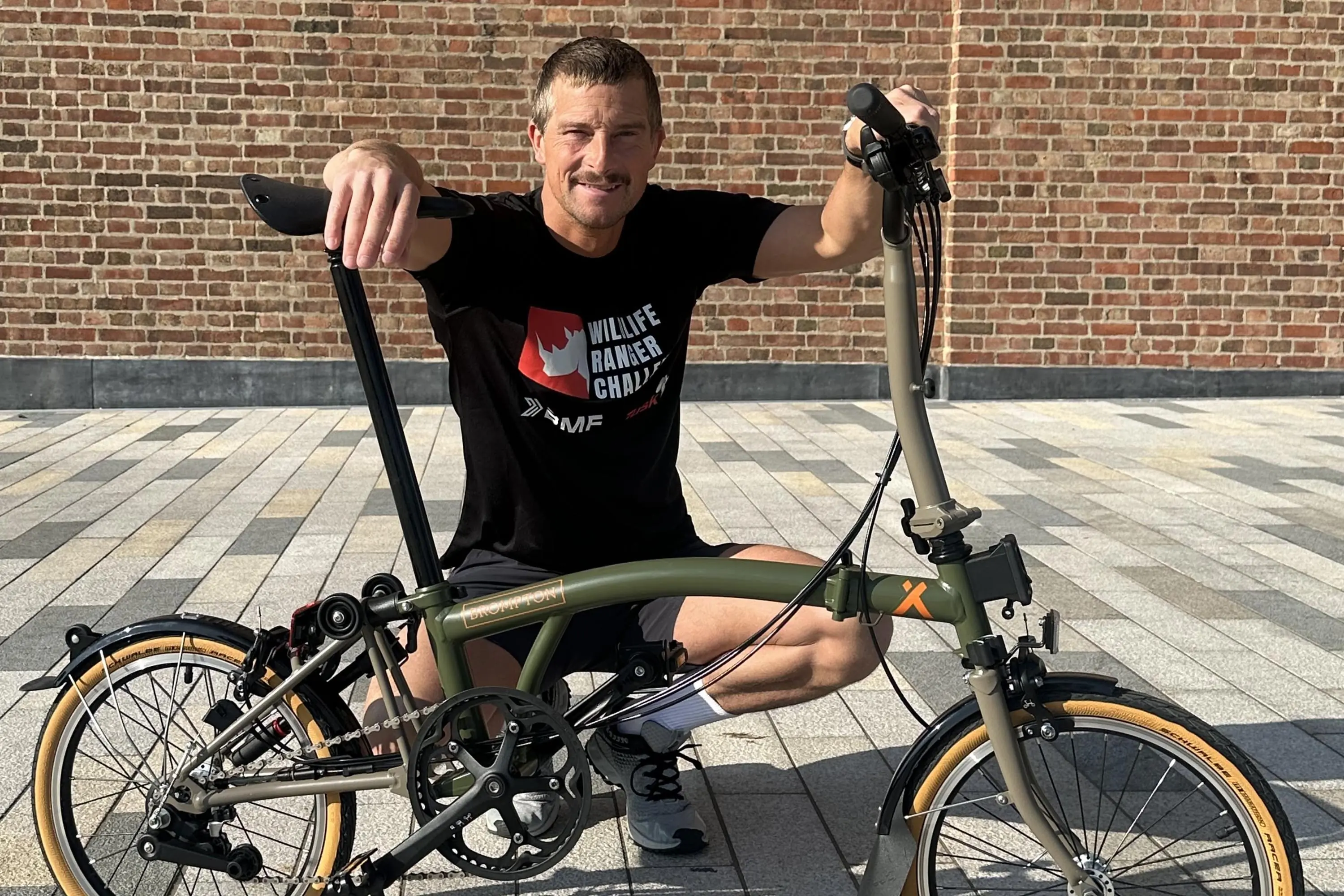 Adventurer Bear Grylls poses with a foldable bicycle.