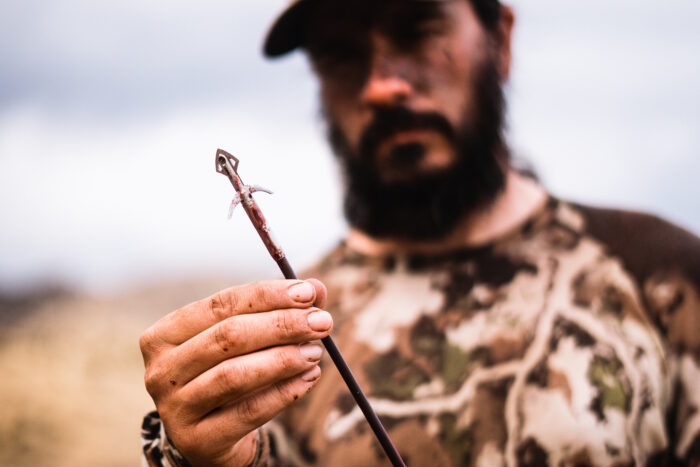 A focused hunter carefully inspecting a sharp broadhead 