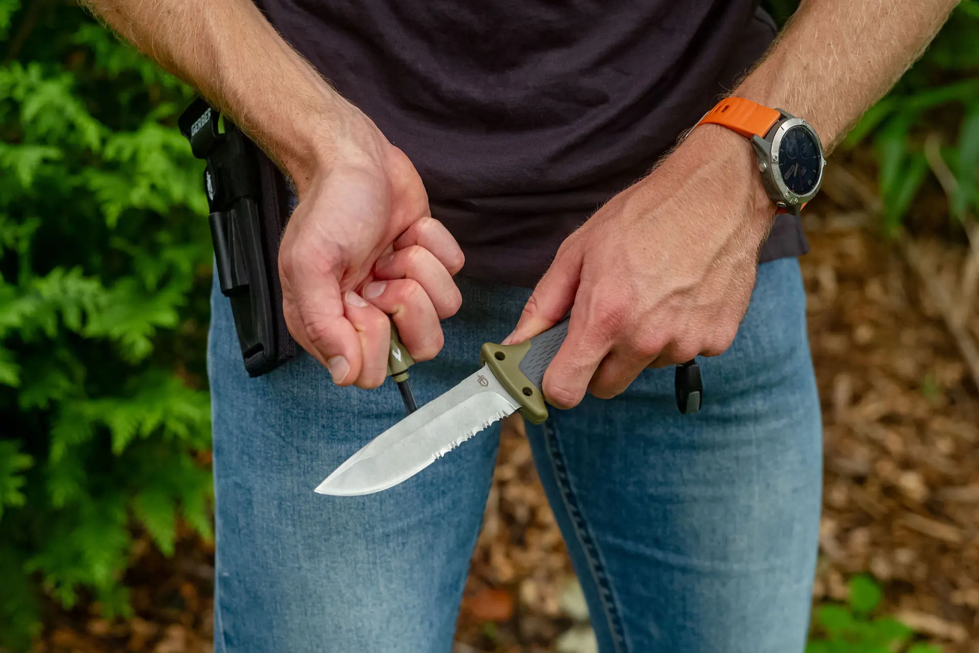 A man uses the Ultimate Knife for chores around camp. 