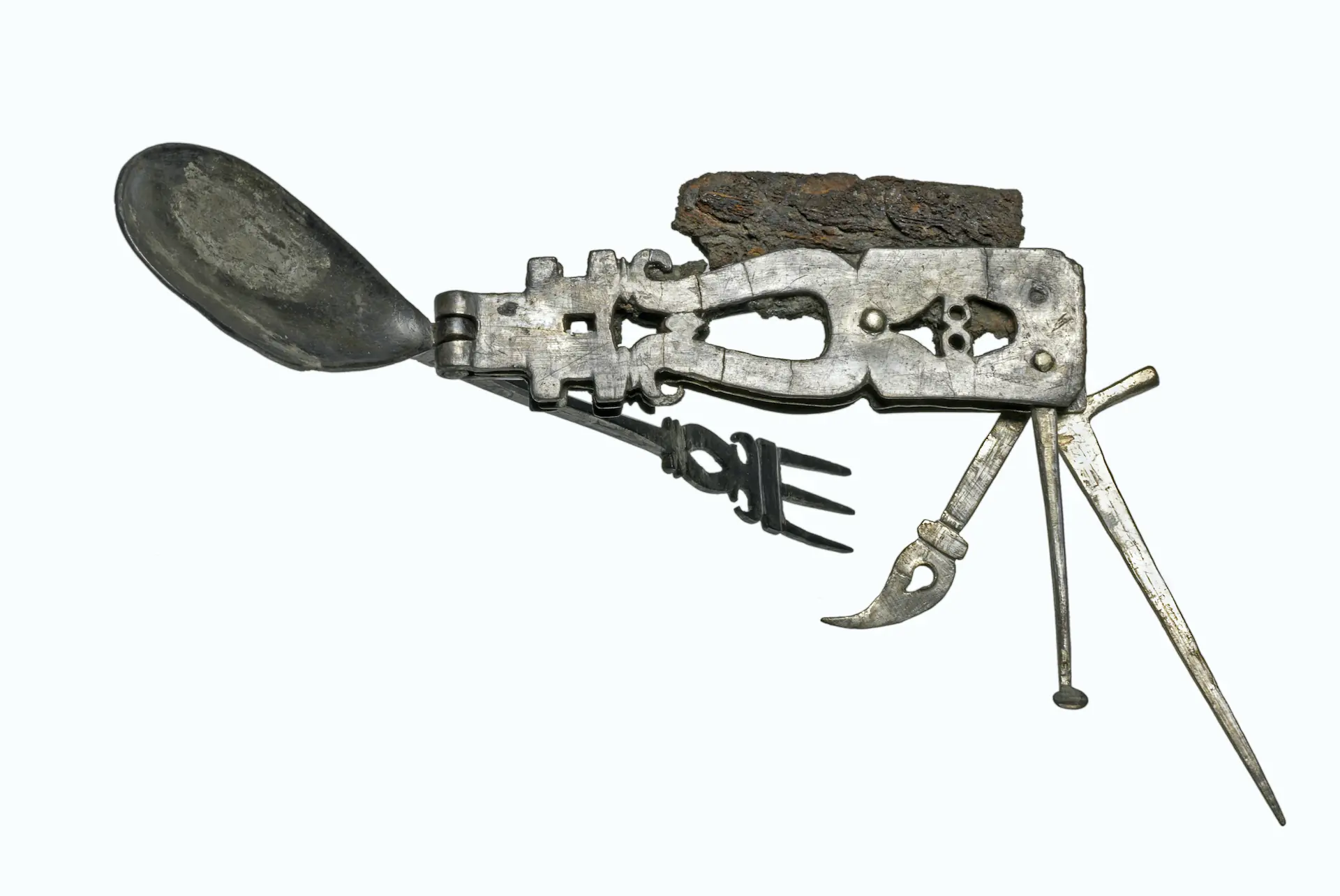 A rusted ancient multitool with spoon, spatula, pick and blade extending. 