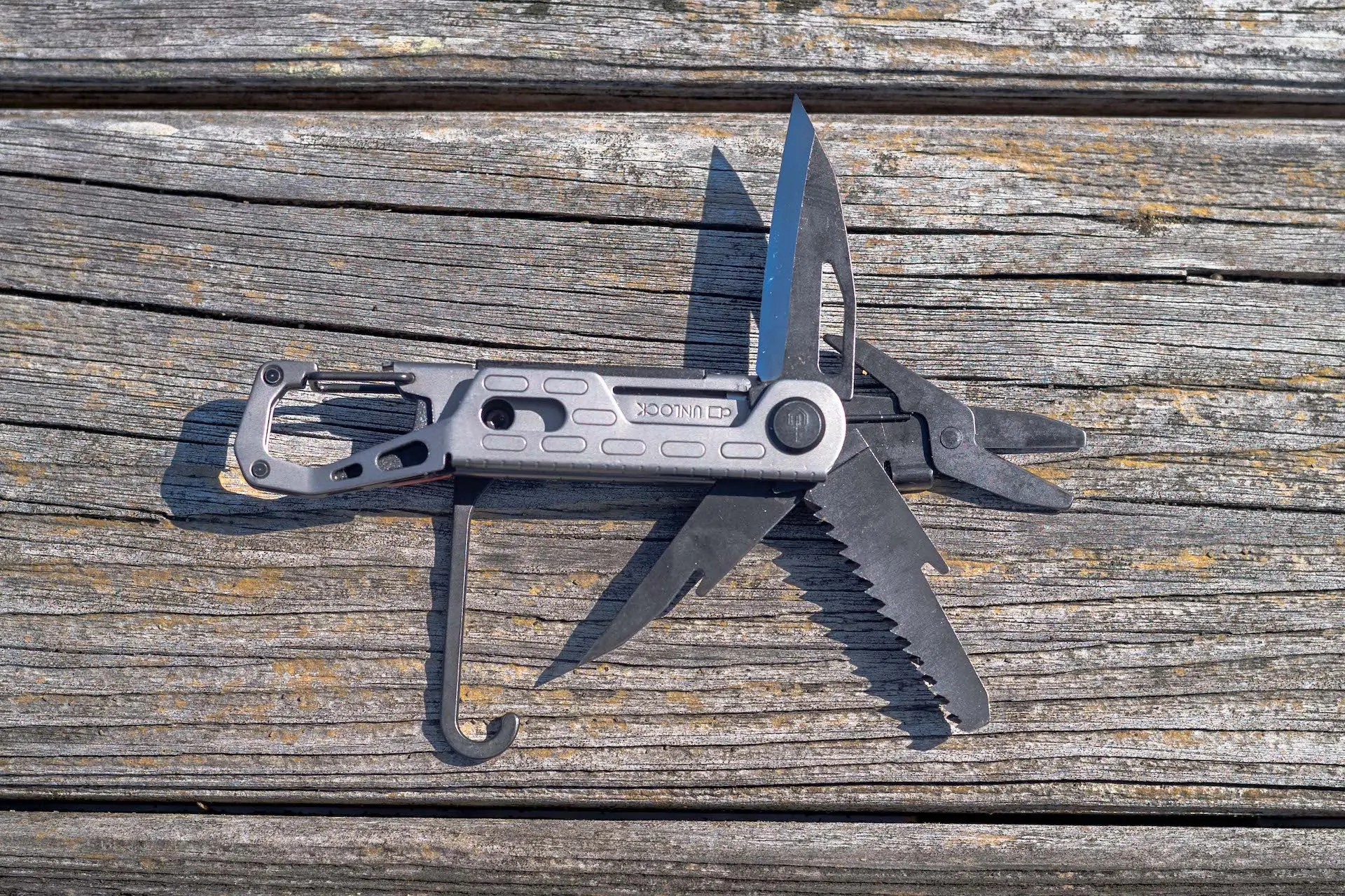 A Gerber Stake Out rests on a wooden picnic table with its tools extended. 