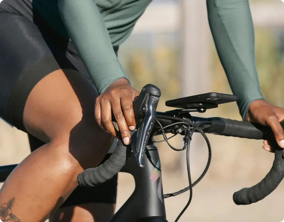a woman rides a road bike with a Peak Designs phone mount