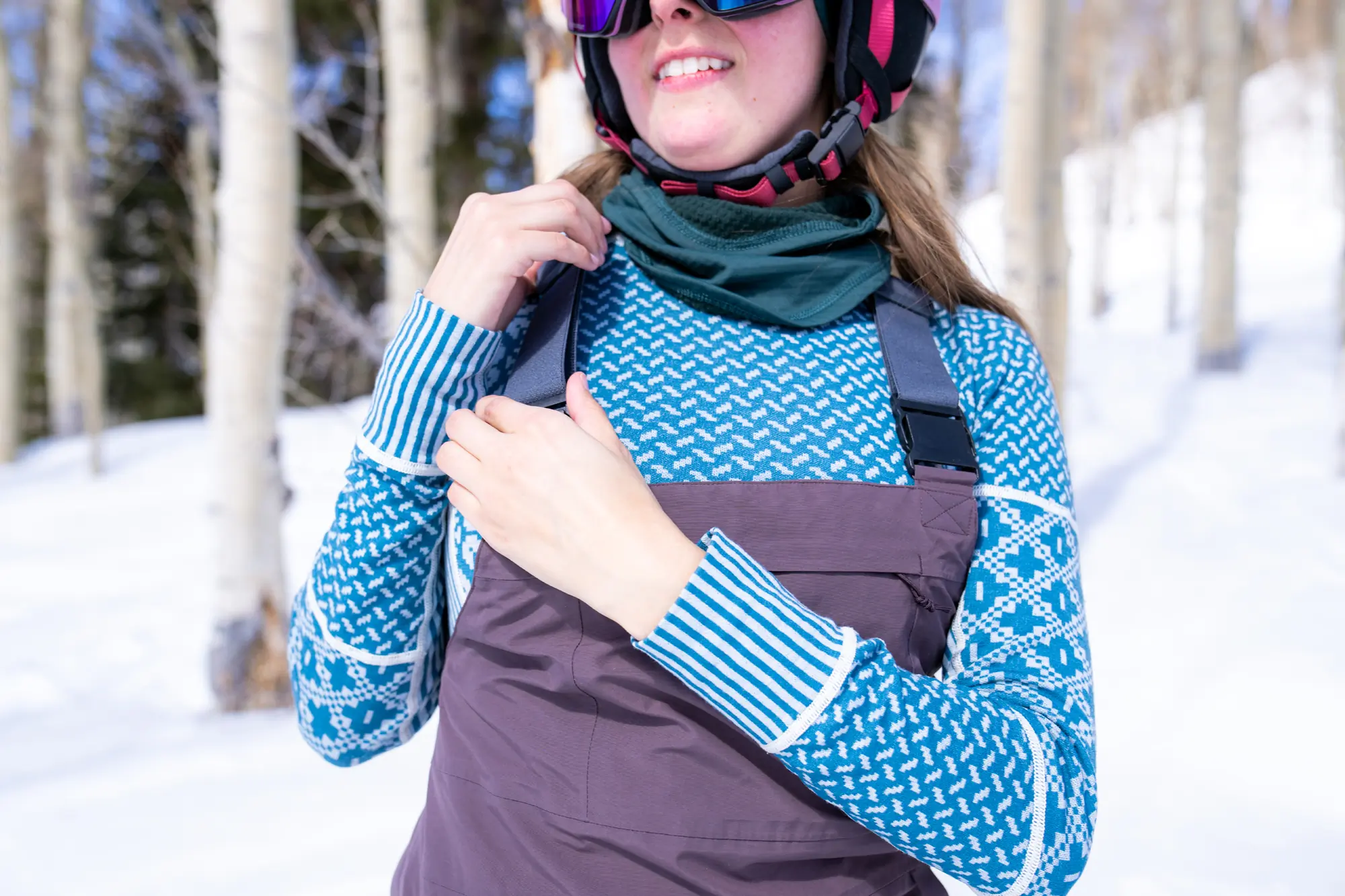 female skier adjusting the bib strap over a base layer top