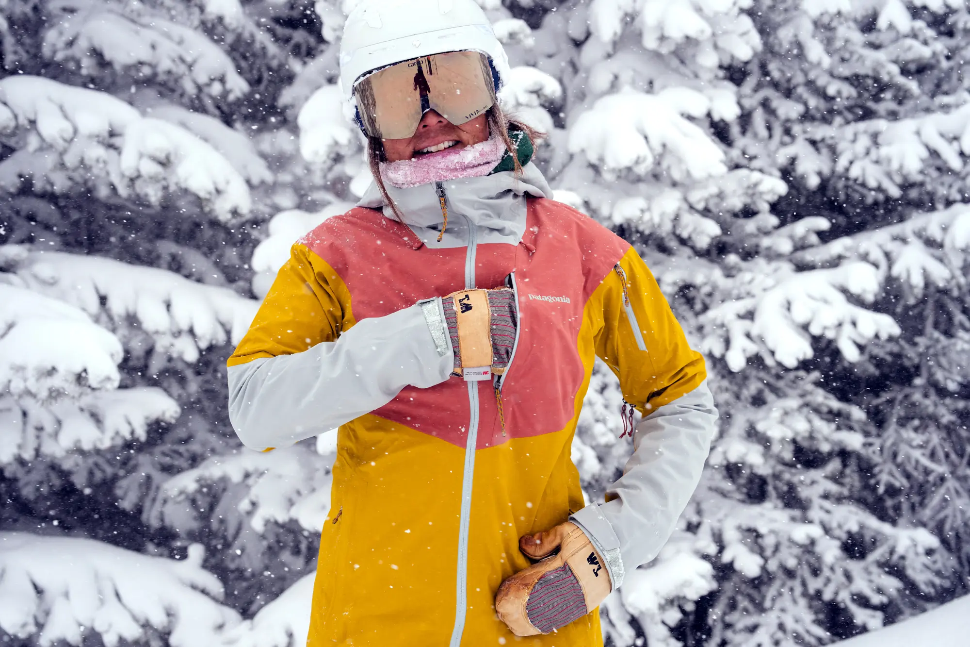 woman putting mitten into ski jacket pocket during snowfall 