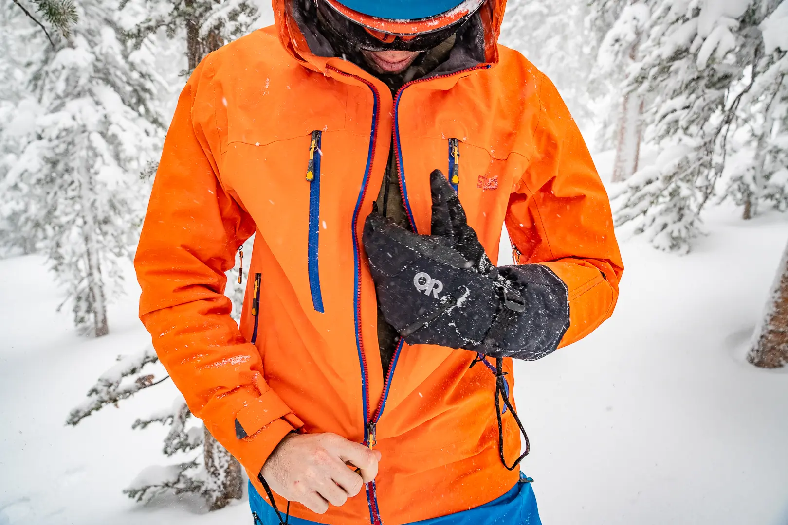 man wearing winter mittens and bright orange ski jacket 