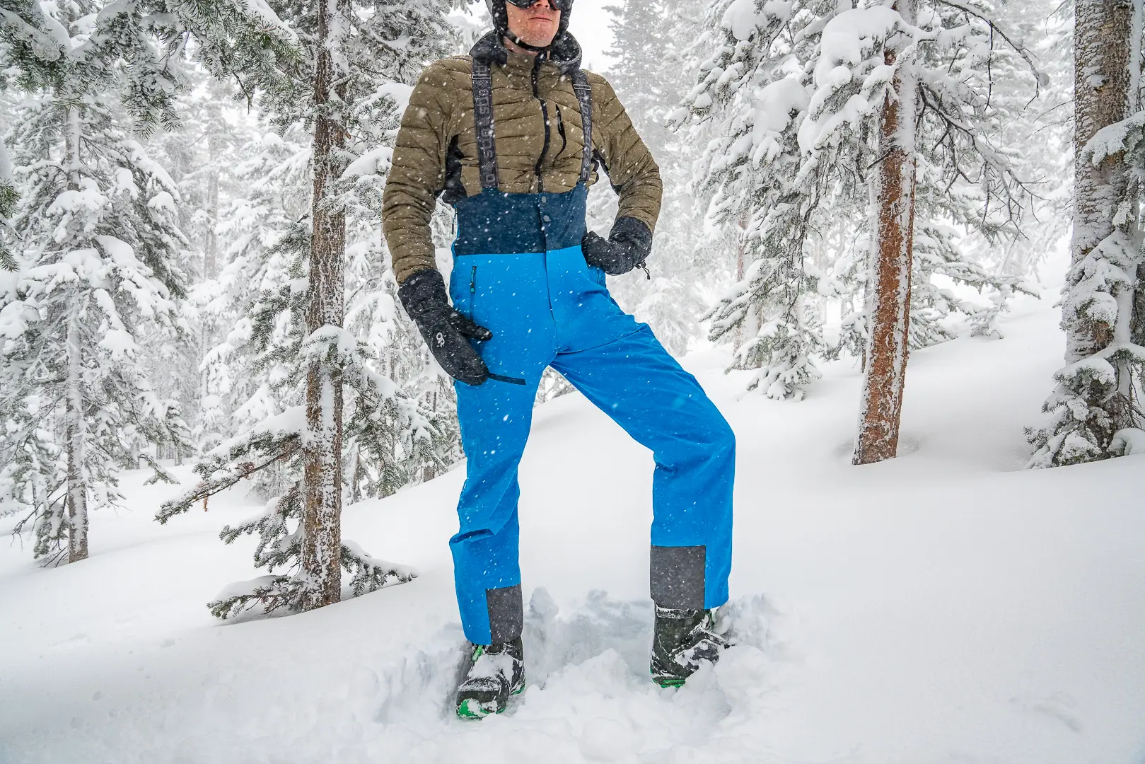 man facing camera with down jacket and men's ski bibs on 