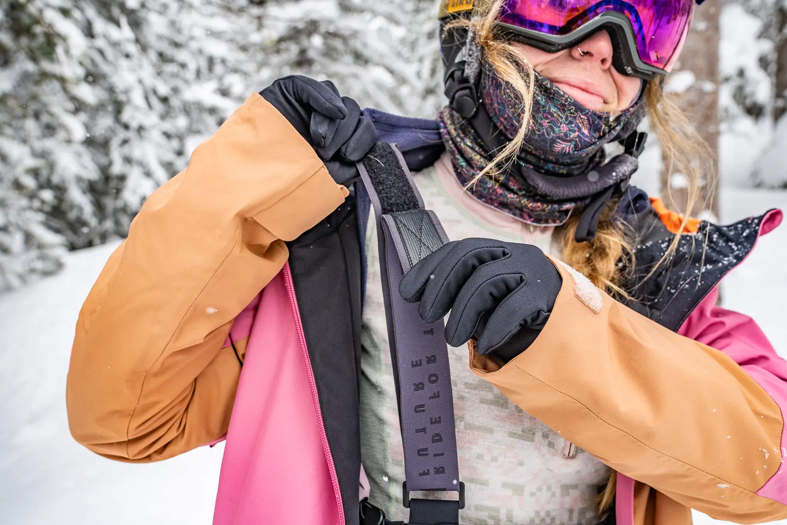 woman opens velcro strap on ski bibs 