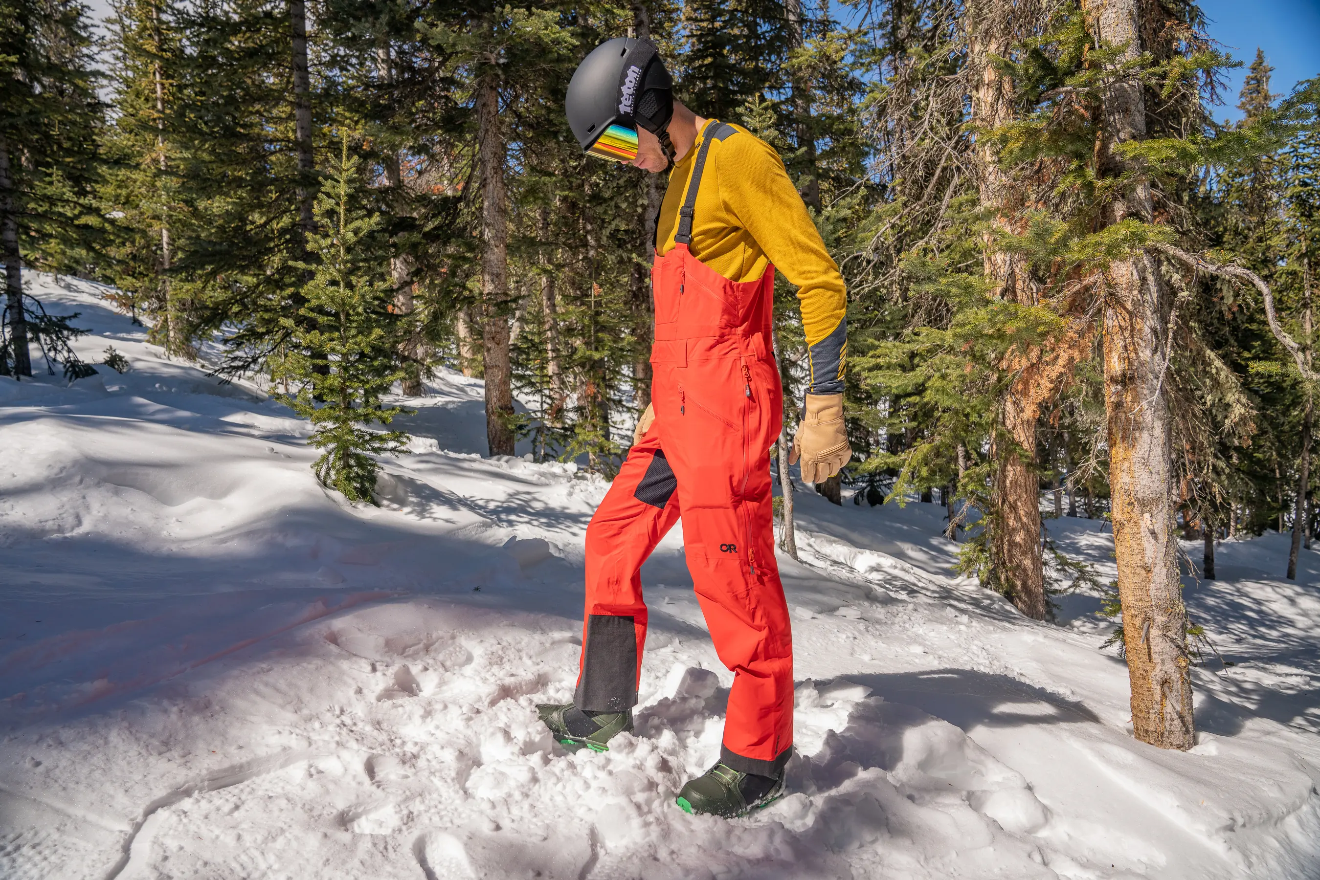 side view of man wearing ski bibs in woods 