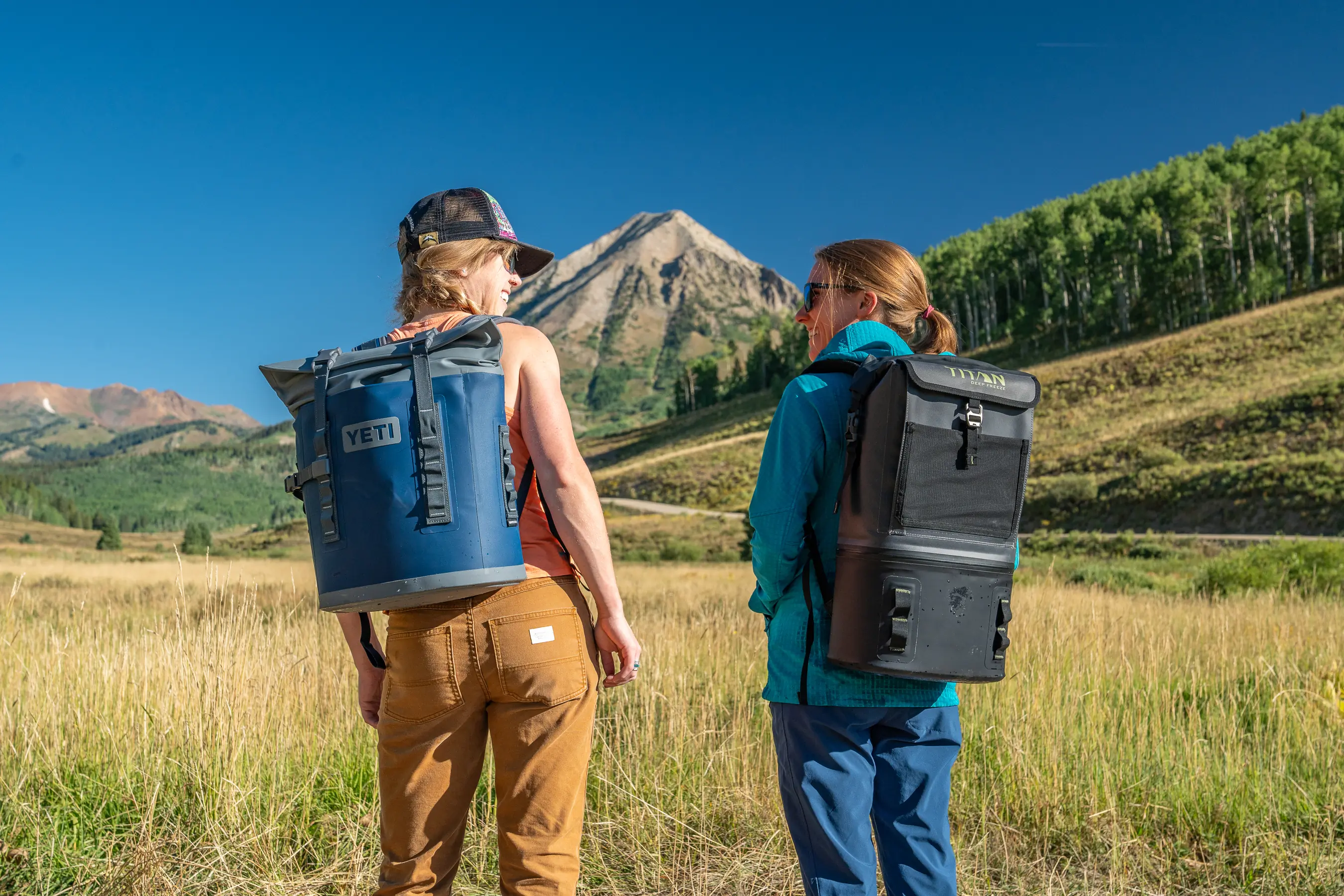 two women wearing backpack coolers