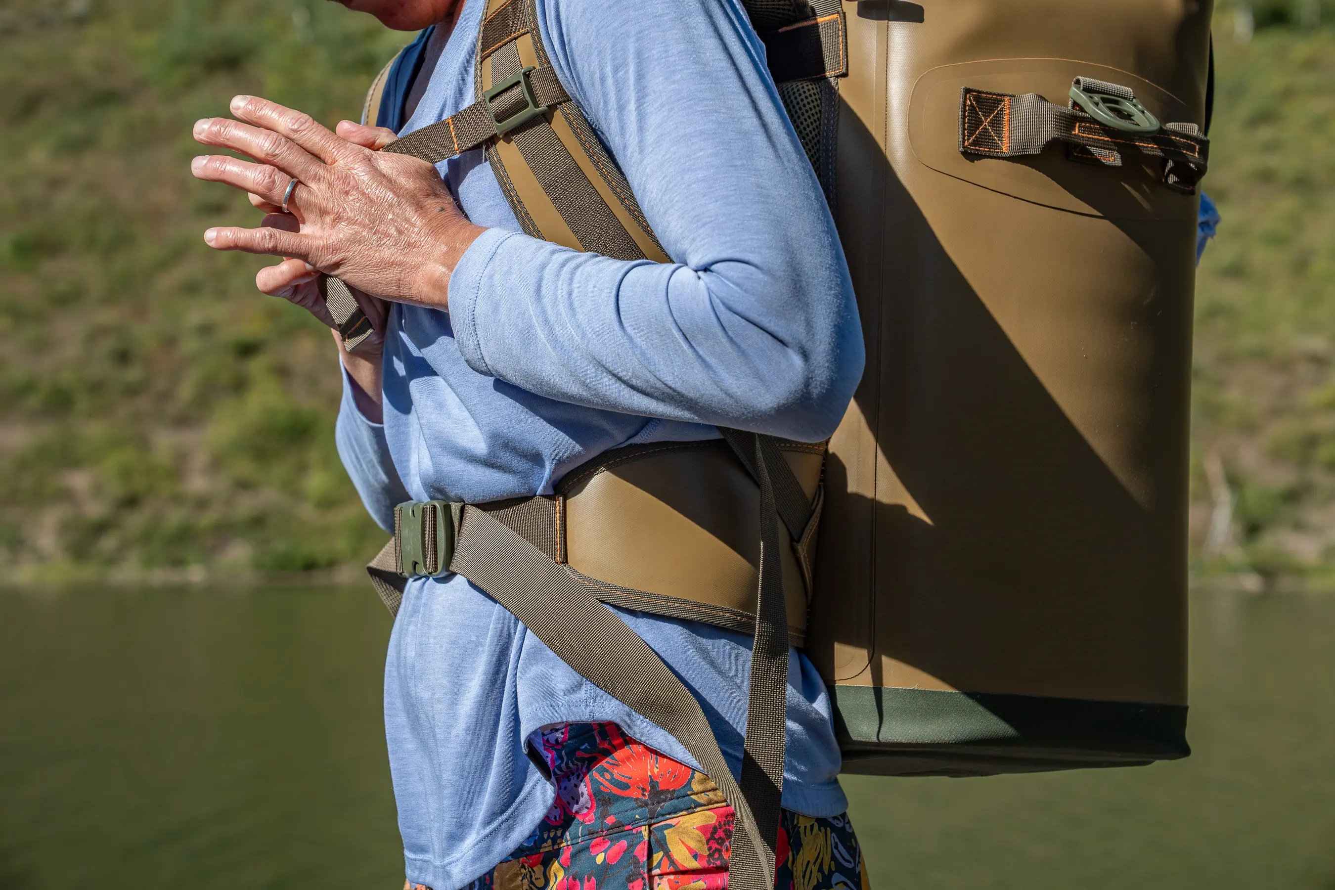 person closing sternum strap on backpack cooler