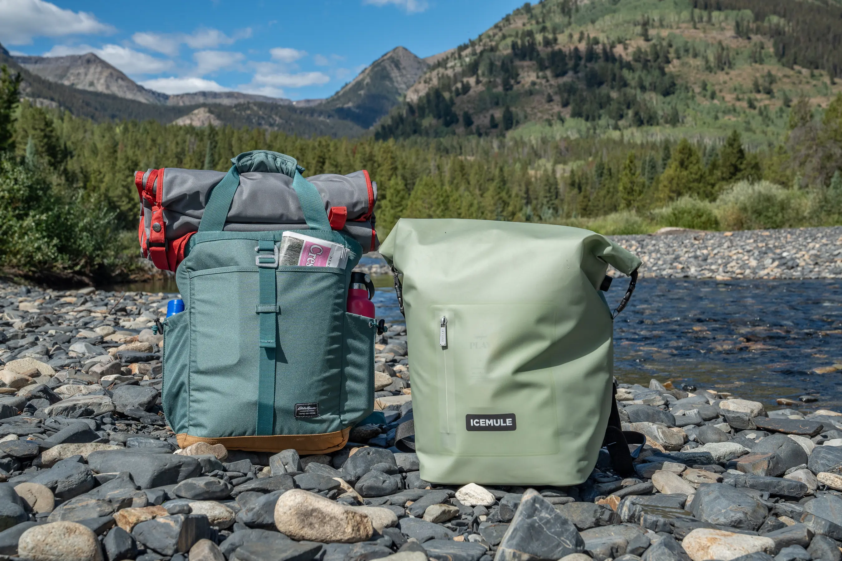 two backpack coolers by the river