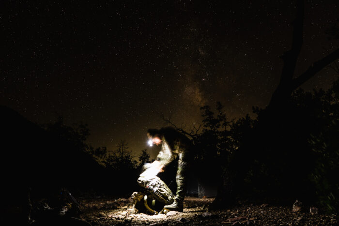 Hunter using their headlamp to looking within their backpack at night