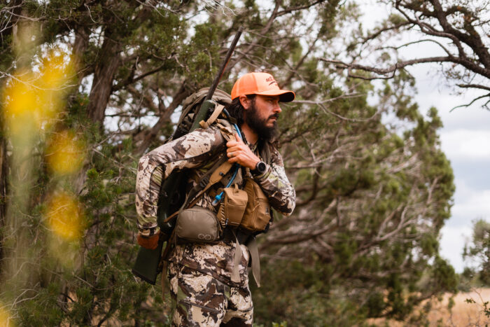 hunter adjusting his rifle sling on his right should while on a hunting trip