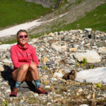 GearJunkie author Kaylee Walden in a fleece and running shorts sitting on a rock in the alpine