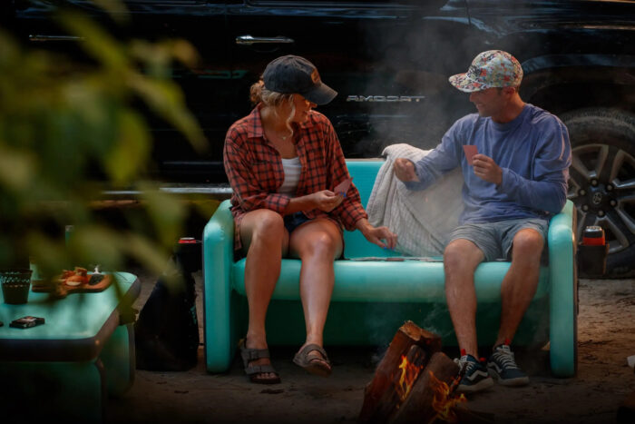 two people sit on an inflatable couch in a parking lot