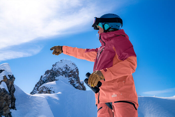 a woman wearing a snow jacket and pants points 