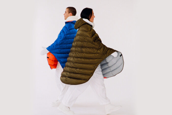 two people wear snowcapes and walk in opposite directions